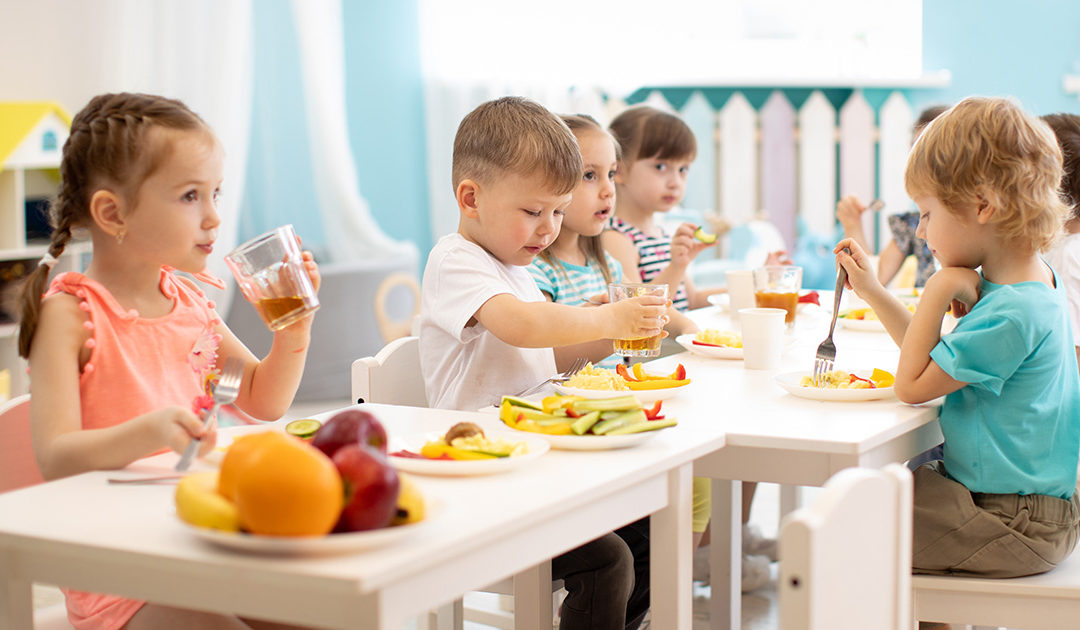 Group of children eating healthy food in day care centre