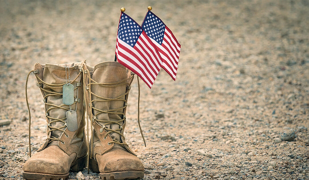 Viejas botas militares de combate con placas de identificación y dos banderitas americanas